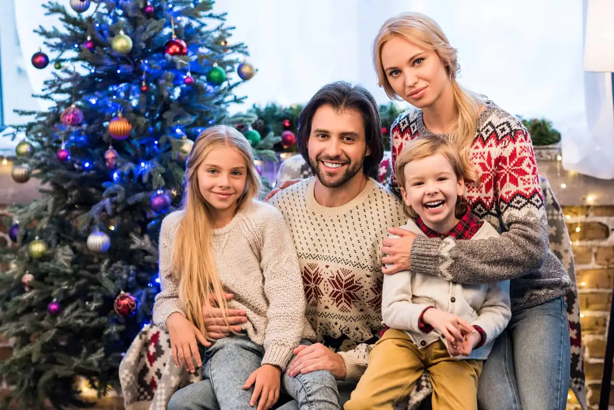 Familie i julesweatre foran juletræet