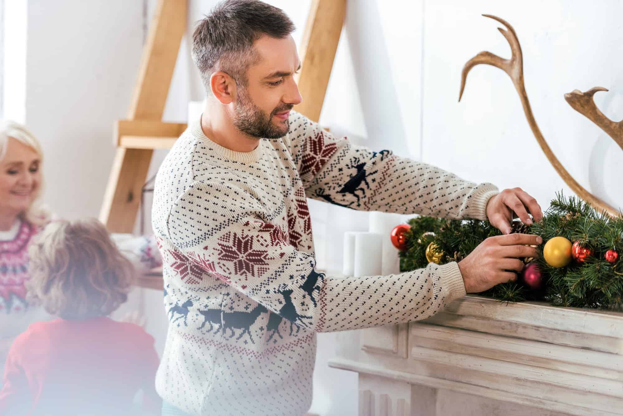 Mand i mønstret julesweater ved en juledekoration